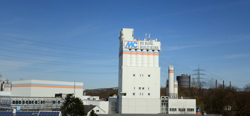 Blik op de poedertoren van MC-Bouwchemie in Bottrop bij schemering vanaf de A42 uit zuidelijke richting.